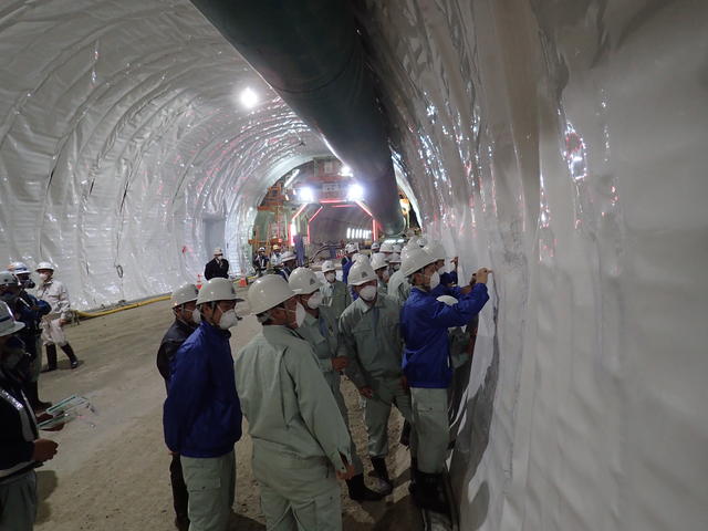 トンネルの防水シートに現場見学記念のメッセージを書込む花巻農業高校の生徒たちの写真